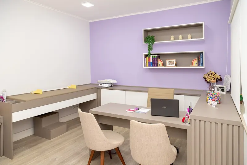 Consultório da Clínica Gioia, com mesa de atendimento e cadeiras para a família